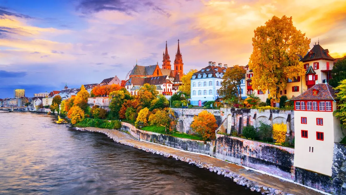 A charming European riverside town with colorful houses, church spires, and golden trees, offering picturesque cultural exploration on a river cruise.