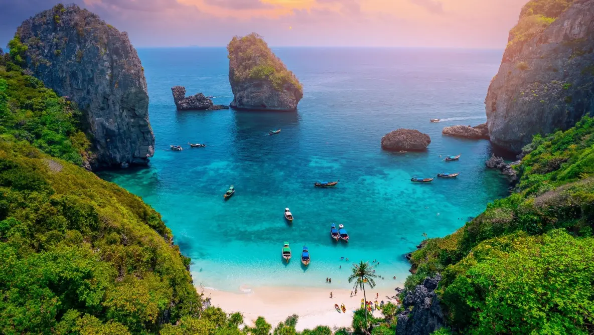 Asia's serene coastal gems feature crystal-clear turquoise waters where small boats rest on a calm sea. A seamless horizon creates a peaceful escape.