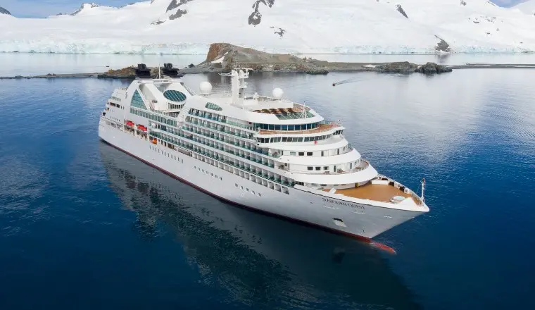 A breathtaking cover of a Seabourn expedition ship with mountains, showcasing 2026 Antarctica and Arctic itineraries.