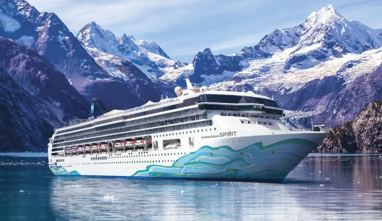 A dynamic cover of an NCL ship, highlighting 2026 “Free at Sea” perks like airfare and specialty dining.