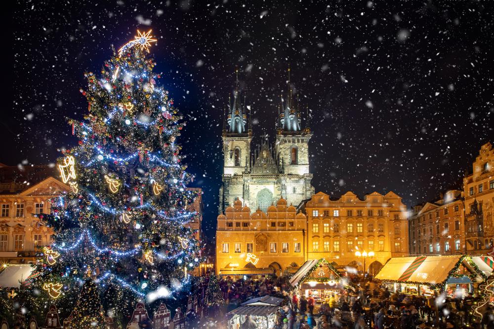 Beautiful view to the old town square of Prague during night time with a Christmas market in winter time with snow falling, Czech Republic.