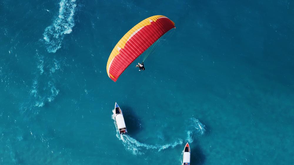 Parapente con mar azul. Dos hombres volando en parapente en lo alto del cielo.