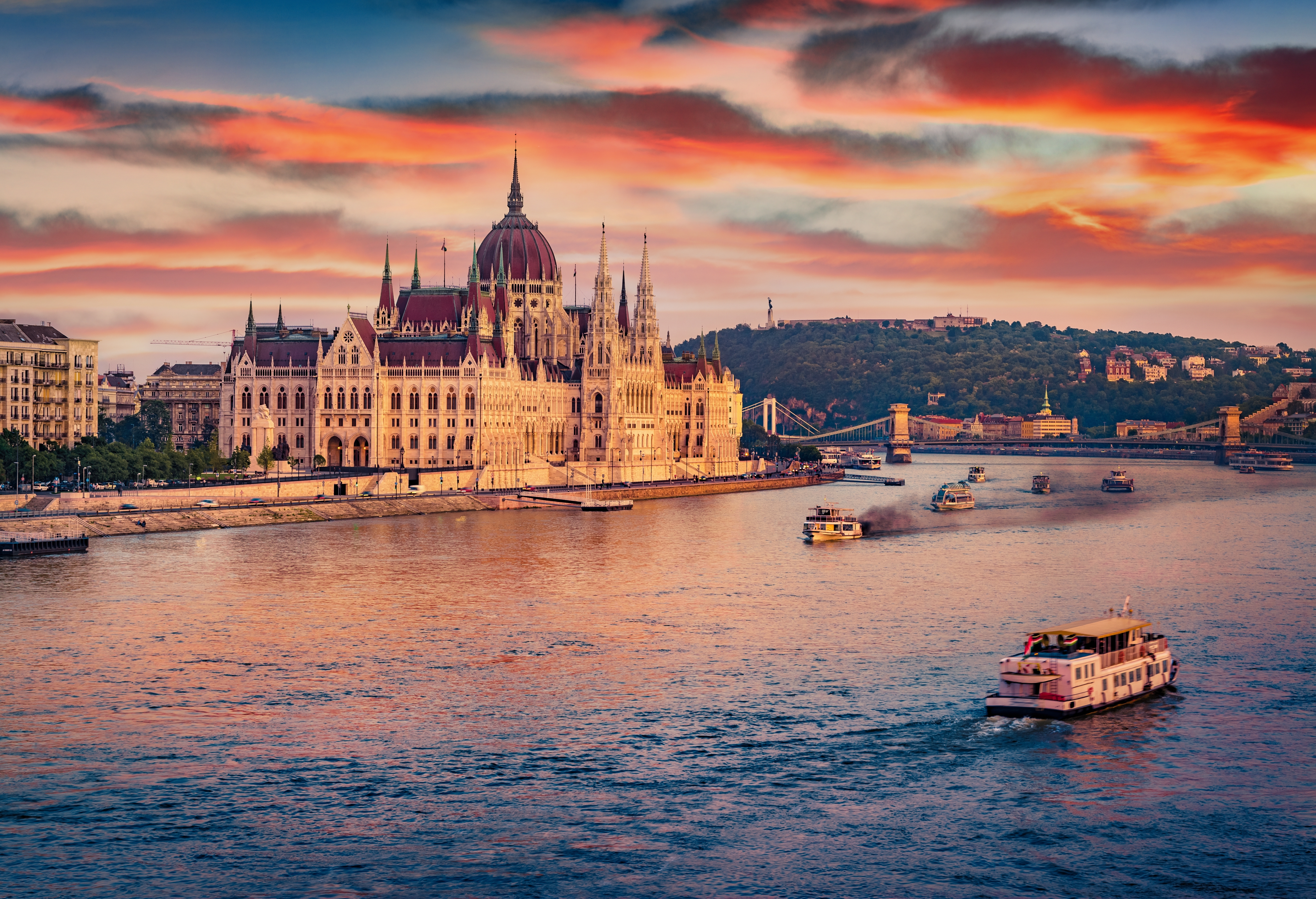 Old pleasure boats on Dunabe river with Parliament house on background.