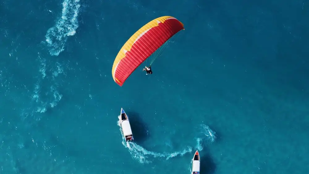 Parapente con mar azul. Dos hombres en parapente en lo alto del cielo.