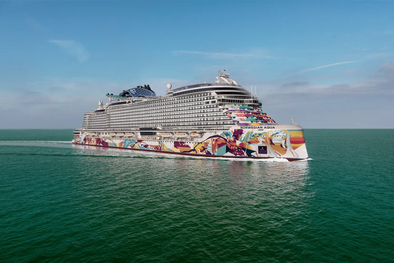 El Norwegian Aqua navega por mar abierto, mostrando su vibrante diseño de casco y su moderno lujo como uno de los buques insignia de Norwegian Cruise Line.
