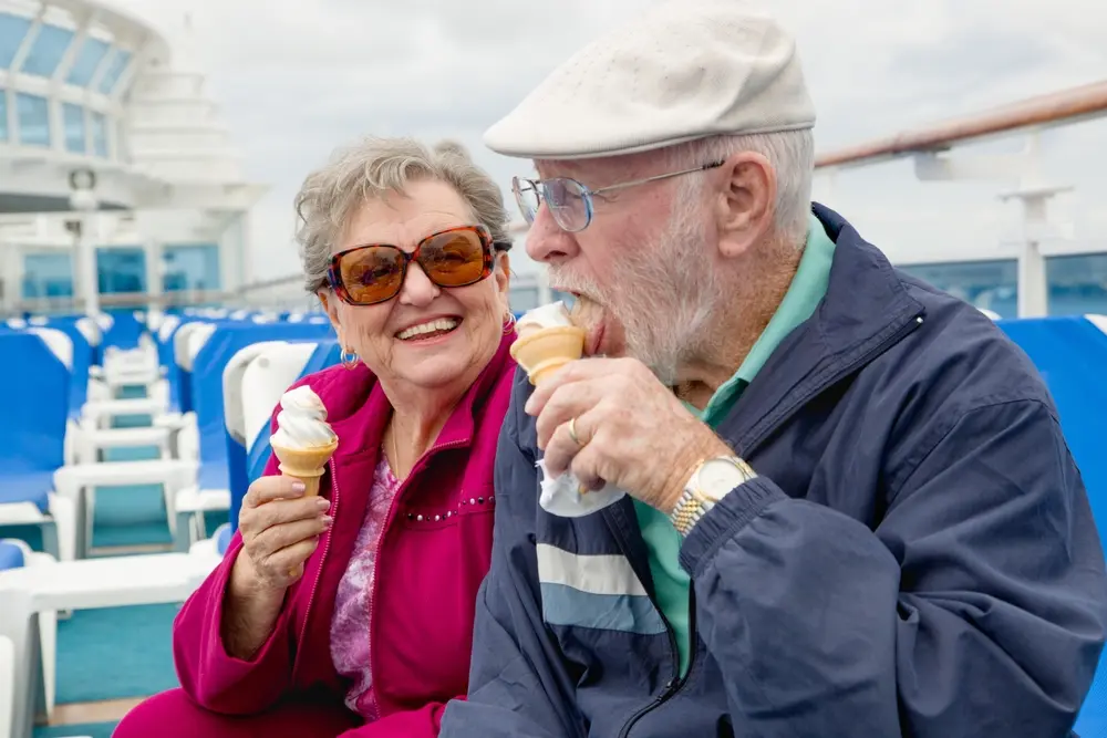Feliz pareja de adultos mayores disfrutando de un helado en la cubierta de un crucero de pasajeros de lujo.