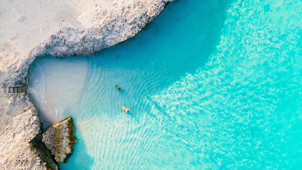 Tres Trapi Steps Triple Steps Beach Aruba, una playa popular para bucear y hacer snorkel, un par de hombres y mujeres en un océano cristalino en el Caribe relajándose en la playa durante las vacaciones