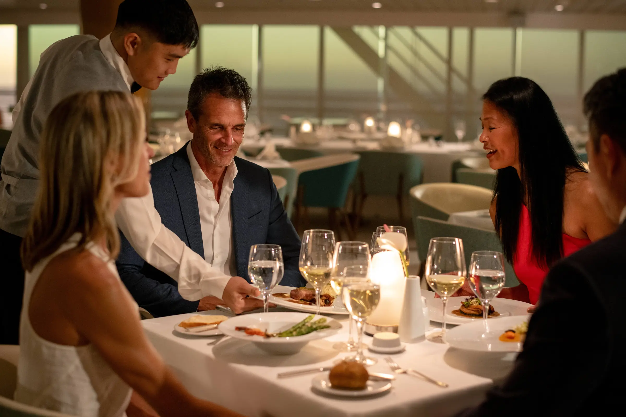 Guests share a lively evening meal at La Veranda, one of the m/s Paul Gauguin's open-seating restaurants serving French-Polynesian cuisine.