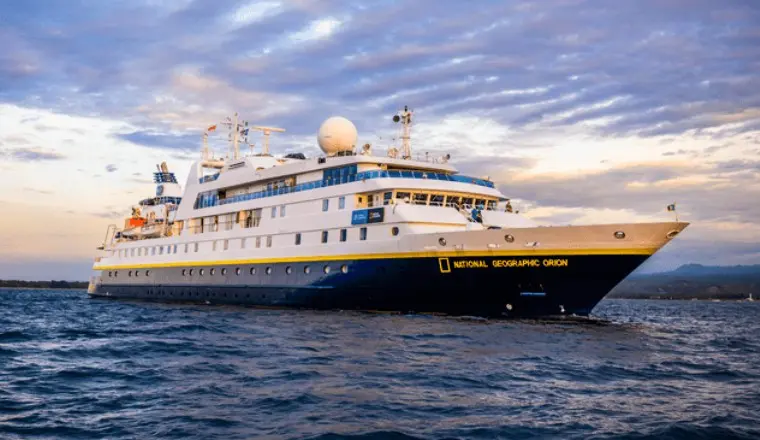 The National Geographic Orion sails beneath a golden sunset sky, one of Lindblad Expeditions' intimate ships built for close encounters.