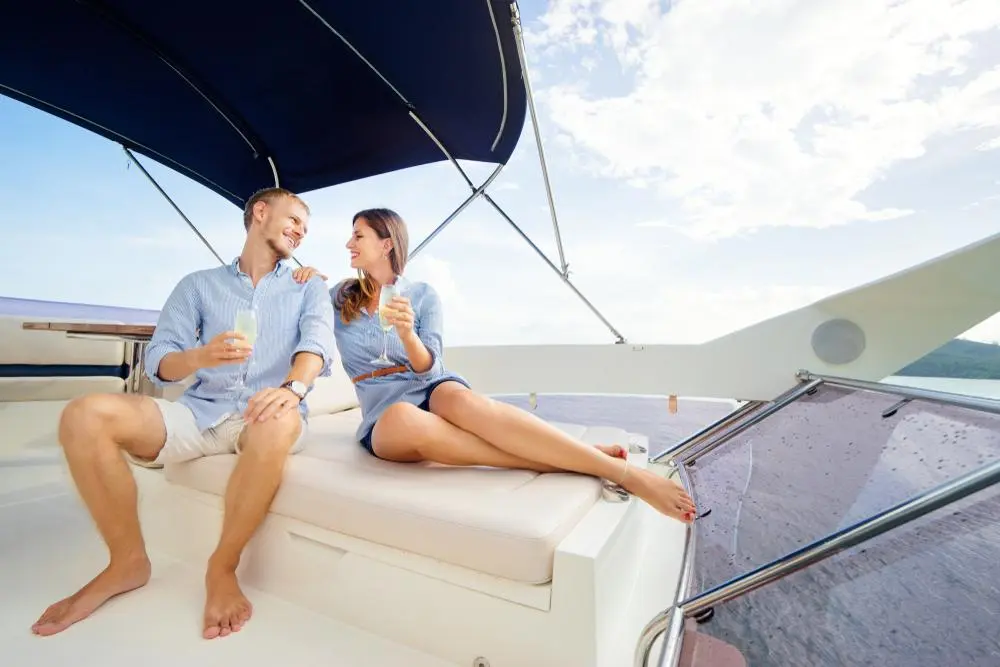Romantic vacation and luxury travel. Young loving couple sitting on the sofa on the modern yacht deck. Sailing the sea.