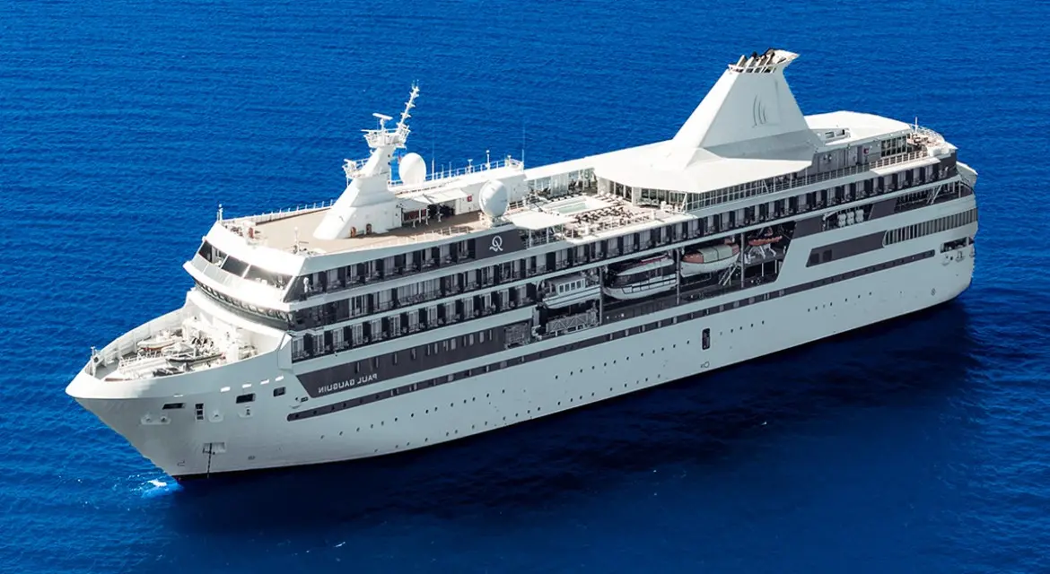 A close aerial view of the m/s Paul Gauguin reveals her pool deck, tenders, and sleek profile as she cruises open Pacific waters.