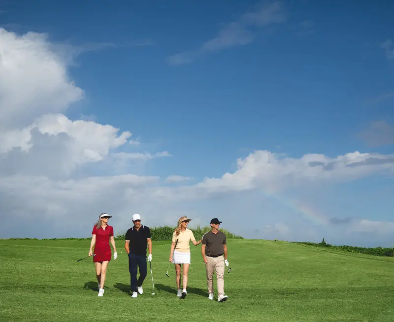 Golfer playing on a scenic oceanfront golf course, with turquoise Caribbean waters and lush green hills in the background
