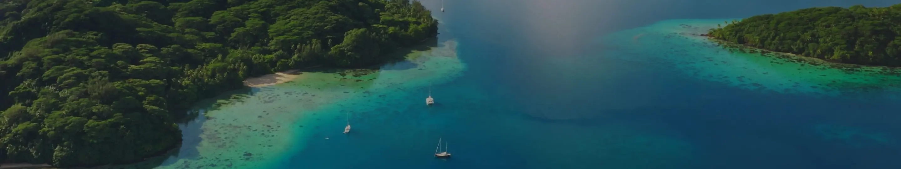 Sailboats drift across a turquoise lagoon beside a lush green island, the kind of secluded French Polynesian scenery only the Paul Gauguin can reach.