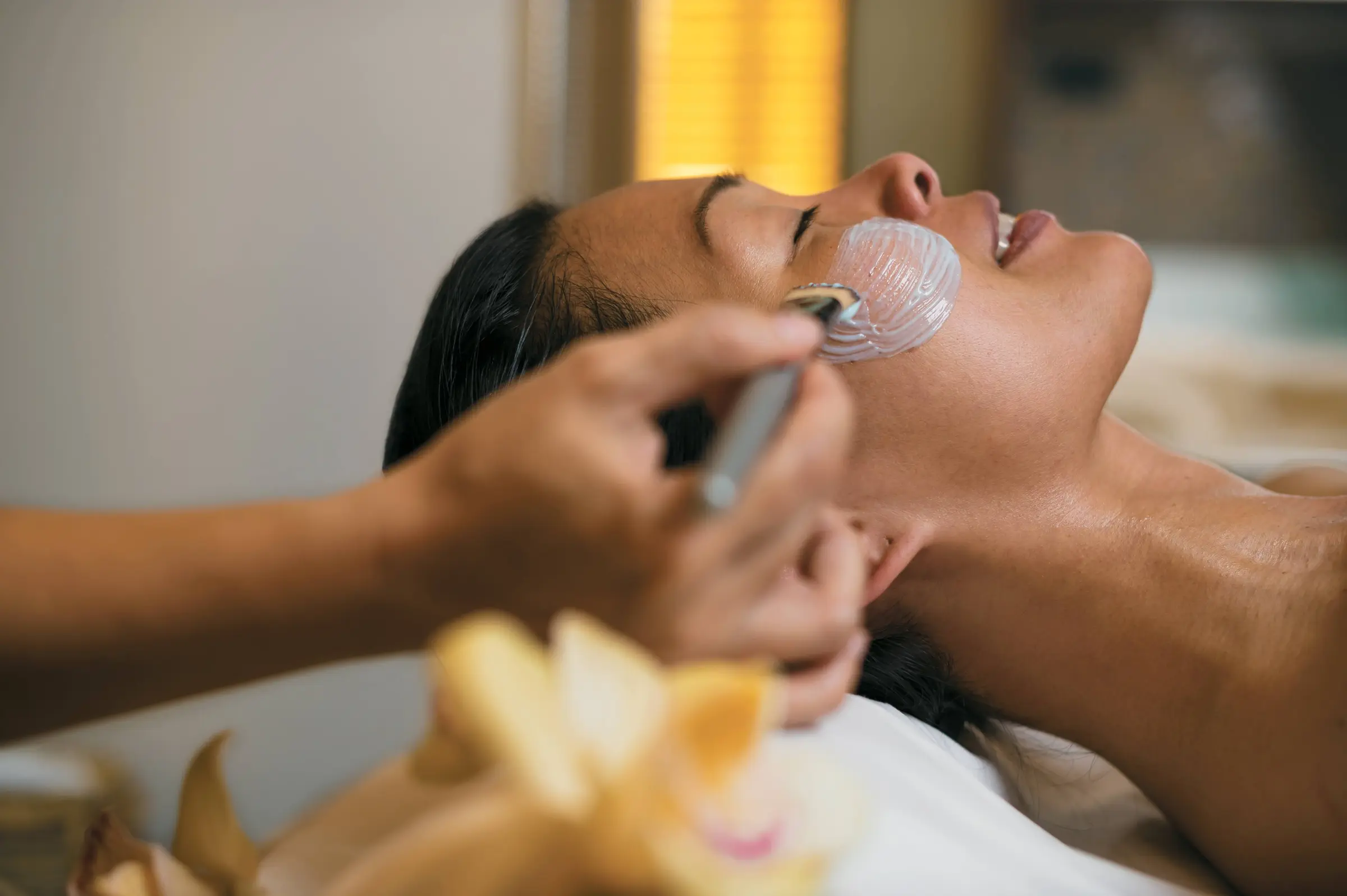 A guest receives a soothing facial treatment at the onboard spa, part of the relaxed, island-inspired wellness experience aboard the m/s Paul Gauguin.